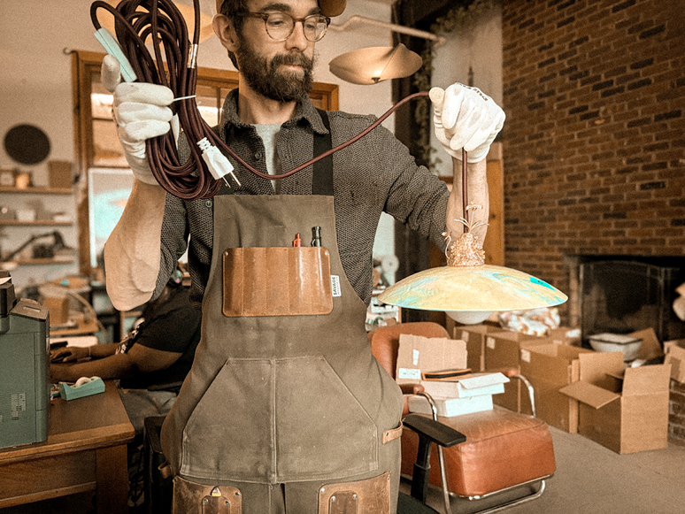 A fabricator working beside a studio window